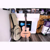 A \ Lâg SL100 Petite Bouche Gypsy Jazz Guitar acoustic on a stand next to the included beige hybrid bag from ECG Music.