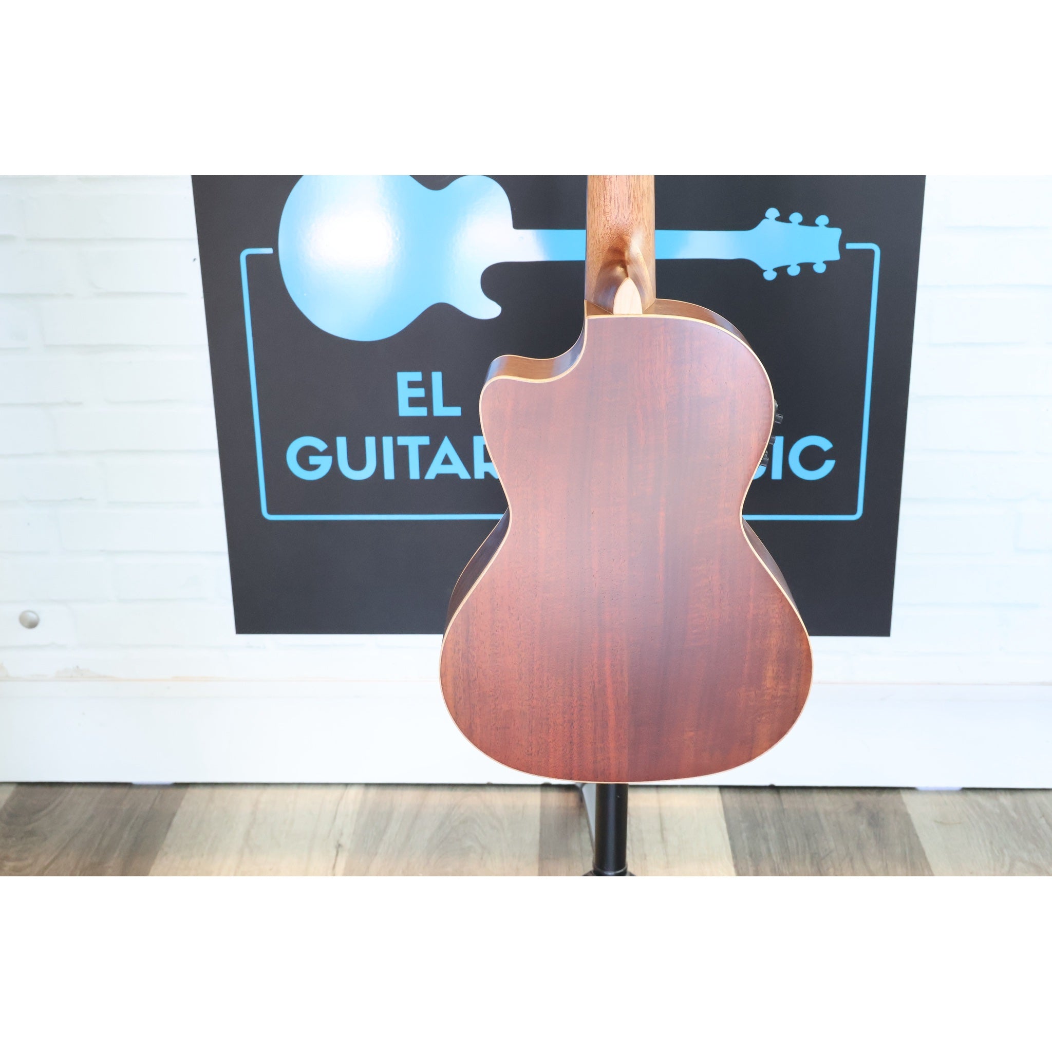 A Kala KA-SA-TE-C All-Solid Acacia Tenor Cutaway Ukulele with Fishman Electronics ukulele  showing the back and wood grain in front of the ECG Music logo at the shop.