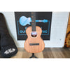 Close-up of a Kala KA-WF-AMHG-T All Solid Mahogany Waterfall Tenor Ukulele at ECGMusic with a natural wood finish stands on a black stand in front of a white brick wall, with a black Kala guitar case on the left ECG Music logo behind it.