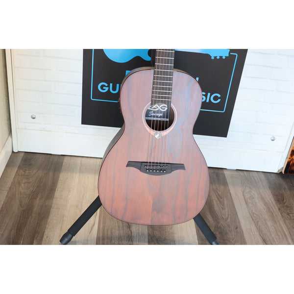 Lâg Sauvage PE Parlor Acoustic-Electric Guitar with a reddish-brown finish and black headstock, displayed on a black stand in front of a white paneled wall with El Cajon Guitars & Music Logo.