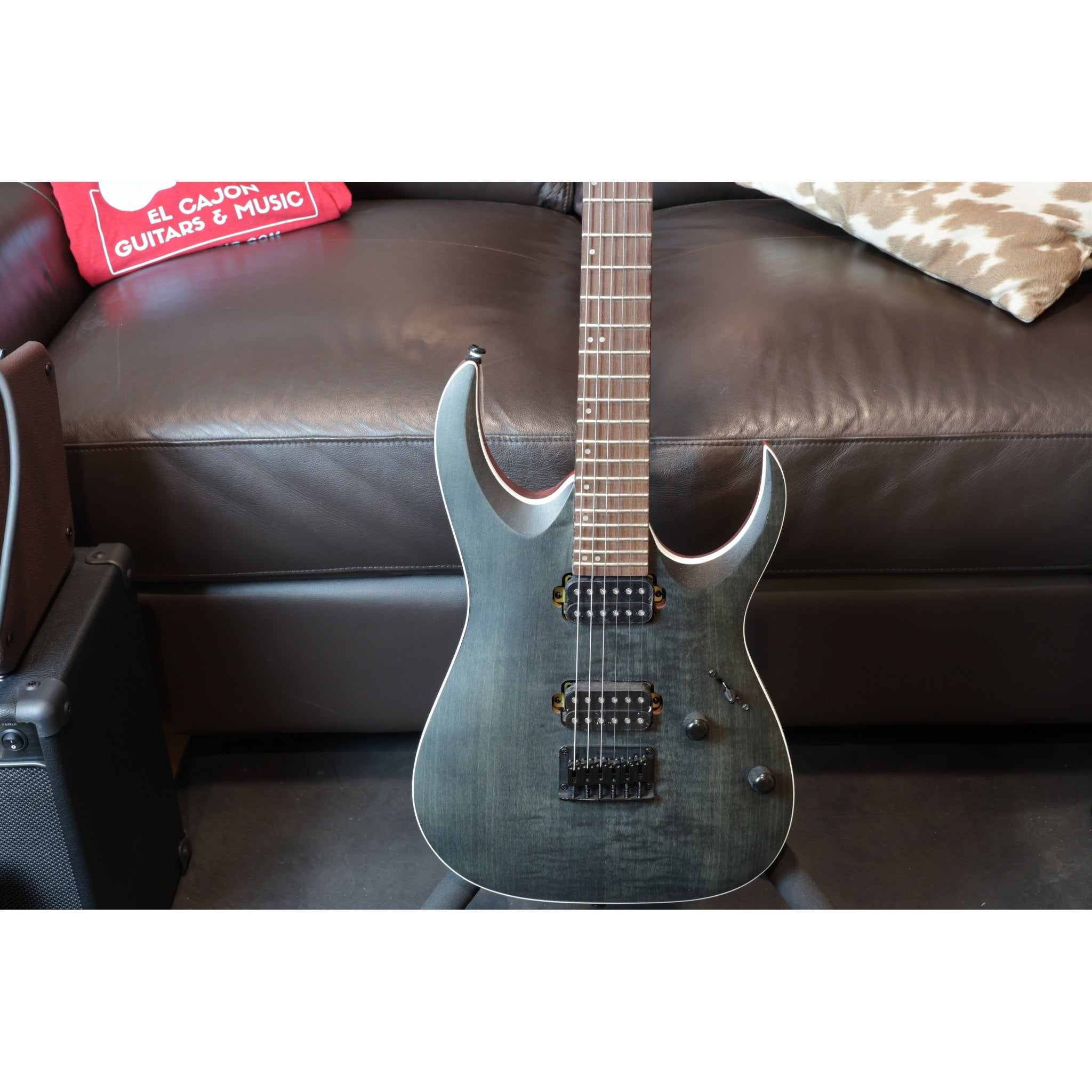 Electric guitar on a brown leather couch with a box in the background