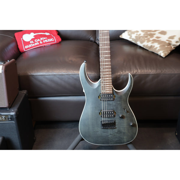 Electric guitar on a dark brown couch with a red box labeled 'El Cajon Guitar Music' in the background.