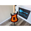 Electric guitar on a stand with 'El Cajon Guitars & Music' sign in the background