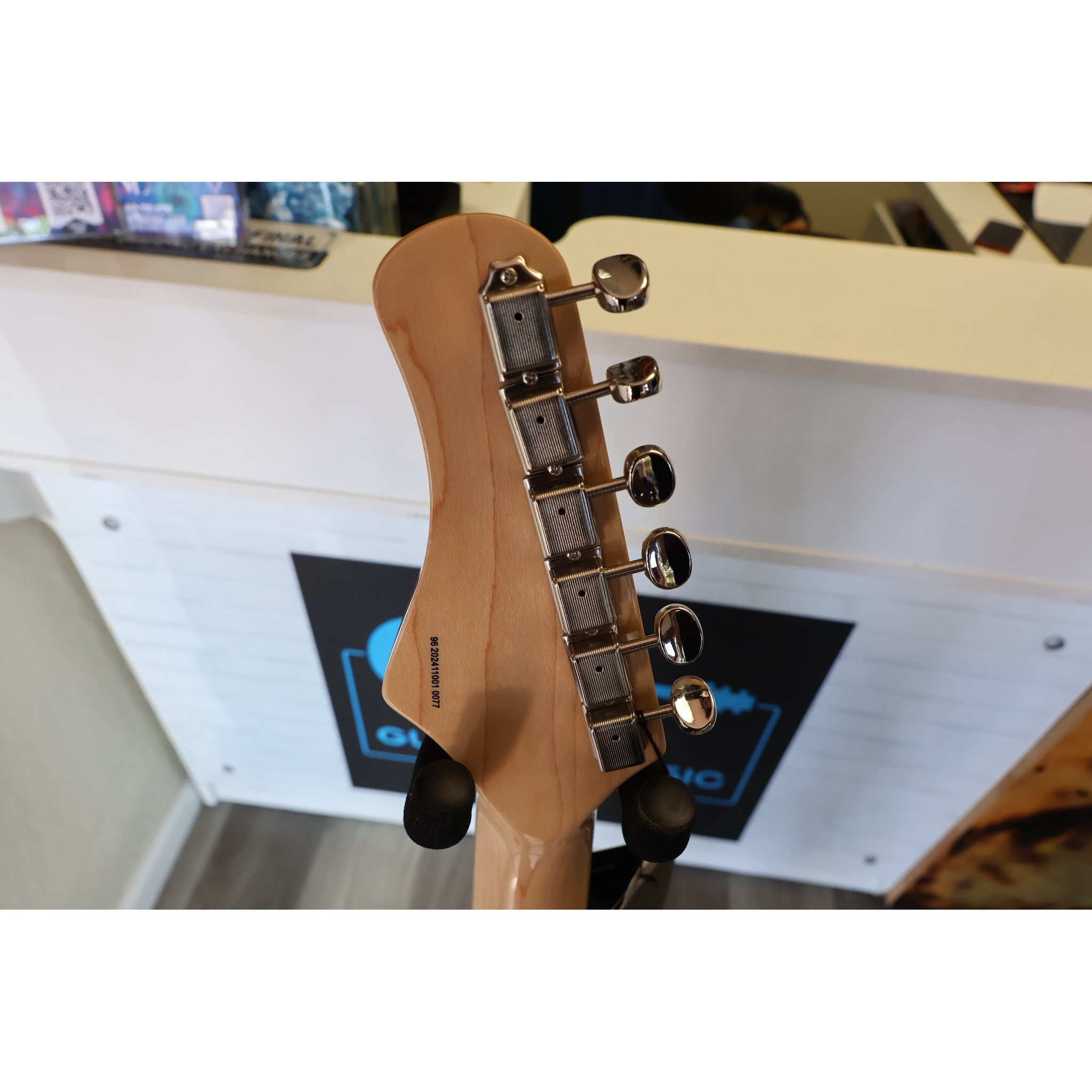 Close-up of a guitar neck with tuning pegs on a blurred background