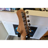 Close-up of a guitar neck with tuning pegs on a blurred background