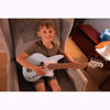 Child holding a white electric bass guitar indoors