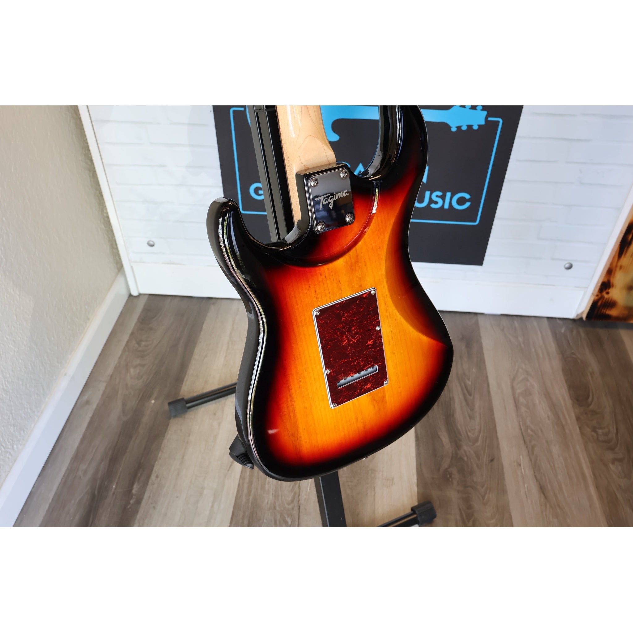 Electric guitar on a stand with a music-themed poster in the background