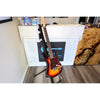 Electric guitar on a stand in a room with a visible brand logo on the wall.