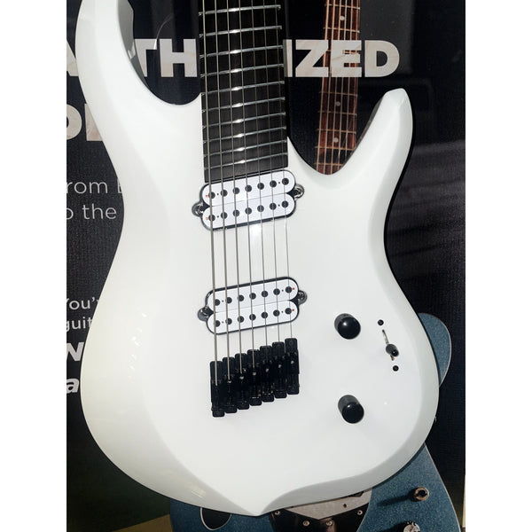 White electric guitar with black details held by a person, with a blurred background.