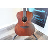 The guitar body cloesup in a stand at the front of El Cajon Guitars & Music with part of the front desk and logo showing.  This guitar is the Lâg Sauvage-A Auditorium Acoustic Guitar with Serial 2511LT20951.