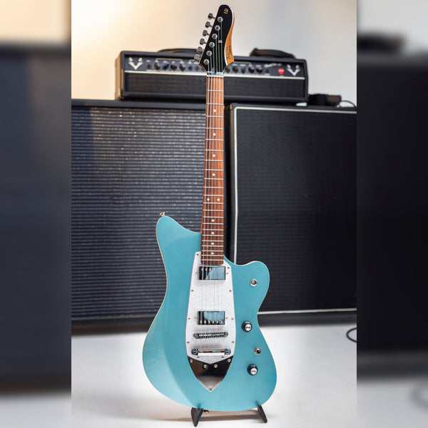 Tagima Rocker UQ Lake Placid Blue on a stand in front of an amp